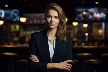 Fototapeta premium Portrait of young businesswoman standing with arms crossed at bar counter