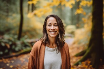 Portrait of smiling woman standing in autumn forest and looking at camera