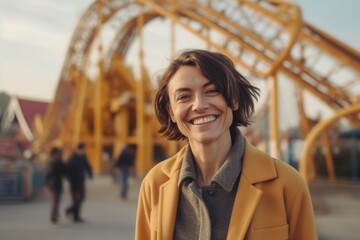 Fototapeta premium Portrait of a smiling young woman in a yellow coat on the background of a metal bridge.