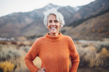 Medium shot portrait photography of a cheerful woman in her 60s that is wearing a cozy sweater against a mountain valley or canyon background .  Generative AI