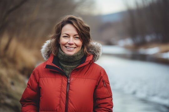 Portrait of a smiling middle-aged woman in a red jacket on a background of winter landscape.
