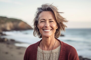 Portrait of happy senior woman smiling at camera on beach at sunset