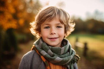 Portrait of a cute little boy wearing scarf and scarf in autumn park