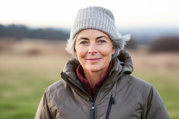 Portrait of smiling senior woman in winter jacket and hat in countryside