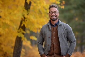 Portrait of a handsome young man standing in the autumn park.