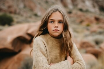 Portrait of a little girl in a beige sweater in the mountains
