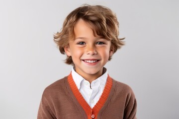 Portrait of a smiling little boy with blond hair on grey background