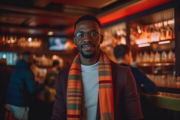 Obraz premium Handsome african american man in glasses and scarf standing in pub