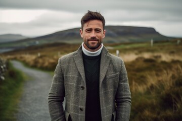 Handsome young man in a coat on a country road in Scotland.