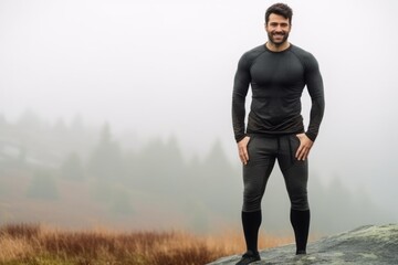 Medium shot portrait photography of a satisfied man in his 30s that is wearing a pair of leggings or tights against a foggy or misty landscape background .  Generative AI