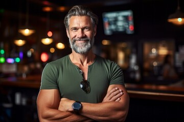 Portrait of confident senior man standing with arms crossed at bar counter