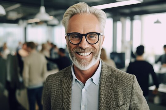 Portrait of smiling senior businessman in eyeglasses looking at camera while standing in office