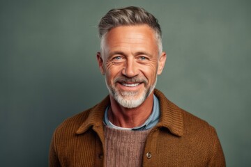 Fototapeta premium Portrait of a handsome mature man smiling at camera while standing against grey background