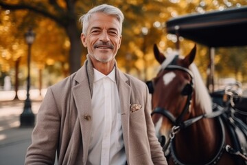 Portrait of a smiling mature man standing with his horse in the park