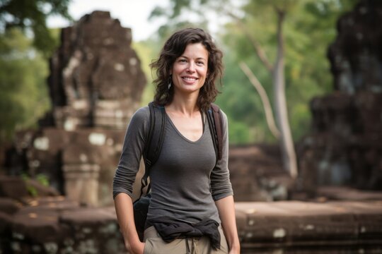 Portrait of happy young woman standing in front of Angkor Wat temple