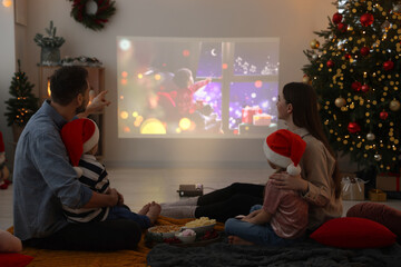 Family watching Christmas movie via video projector in cosy room. Winter holidays atmosphere