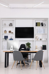 Stylish director's workplace with wooden table, tv zone and comfortable armchairs in office. Interior design