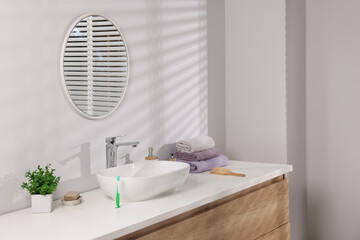 Stylish bathroom interior with vessel sink and round mirror