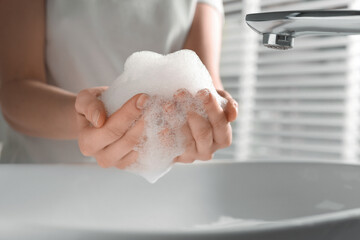 Fototapeta premium Woman washing hands with cleansing foam near sink in bathroom, closeup
