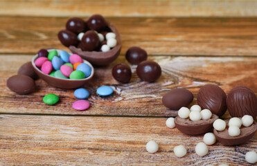 Delicious chocolate eggs and candies on wooden table