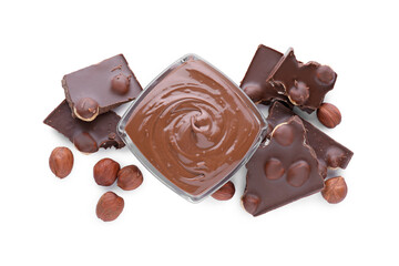 Chocolate pieces, bowl of sweet paste and hazelnuts on white background, top view