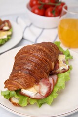 Tasty croissant with brie cheese, ham and bacon on table