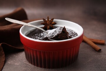 Tasty chocolate pie with anise and spoon on brown table, closeup. Microwave cake recipe