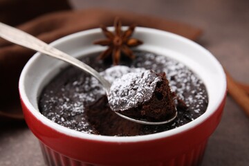 Tasty chocolate pie with anise and spoon on brown table, closeup. Microwave cake recipe