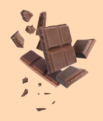 Pieces of chocolate bar falling on beige background