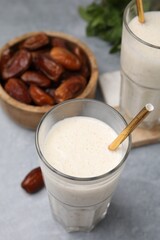 Glasses of delicious date smoothie and dried fruits on light grey table