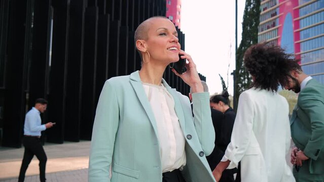 Slow motion. Successful business woman with suit alking and talking by mobile phone. Businesswoman having a call conversation on a cellphone. Executive female chatting using a smartphone at workplace
