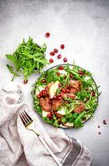 Gourmet salad with grilled chicken liver, green apple, pomegranate seeds and fresh arugula. White...