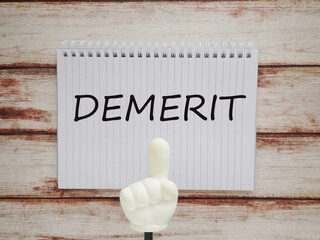 ノートにdemeritデメリットの文字と指差し棒