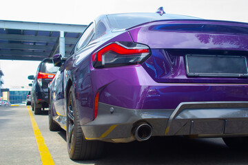 back view of purple sedan bmw cars parking in a row with yellow line on the ground. low angle view
