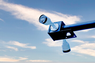 CCTV camera with blue sky background and white clouds, close-up of surveillance camera road safety
