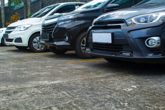 cars parked in a row in outdoor area of a mall car park have white, black, and grey color