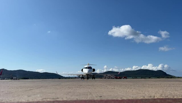 Front view of a white color medium size Bombardier CRK  jet parking in Ibiza&rsquo;s airport, Spain, in a splendid spring day.