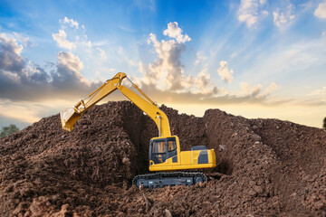 Fototapeta na wymiar Crawler excavator is digging soil in the construction site with sky and sunbeam backgrounds.