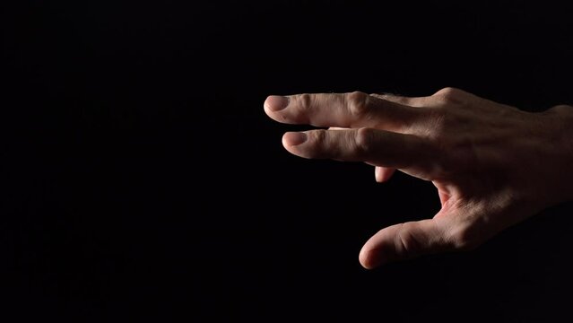 An old man's hand reaches for the light on a black background