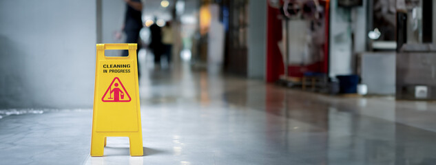 Yellow plastic cone with sign showing warning of wet floor in restaurant in department store -panoramic banner