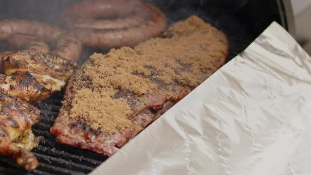 BBQ pork ribs with brown sugar glaze are placed in aluminum foil and wrapped for cooking. Slow motion