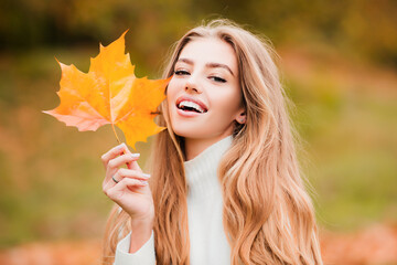Happy smiling woman holding in her hands yellow maple leaves over autumn background. Autumn dream. Woman dreams in autumn fall. Beauty girl dream. Daydreamer woman. Dreams and imagination. - Powered by Adobe