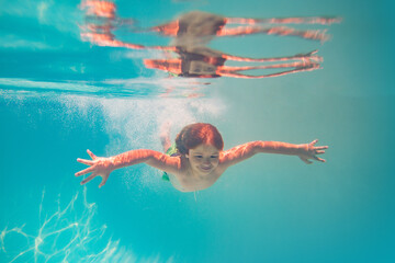 Kid boy swim underwater in summer pool. Summer kids vacation concept. Funny kids face underwater. Child splashing in swimming pool. Summer water sport. Summer vacation with child.