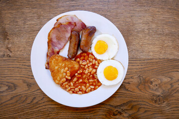 English breakfast on white plate on an old wood table with copy space
