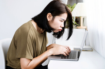 Asian Woman having problems with Blurry Vision and Eye Strain while Working on a laptop sitting too close to the screen, Computer vision syndrome or  digital eyestrain symptoms concept