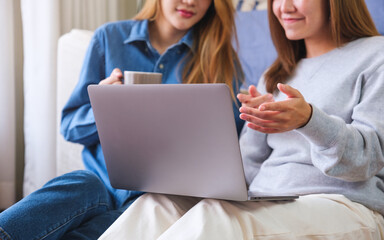 Closeup of a young couple women working and using laptop computer together at home