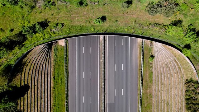 Steady top down aerial view of cars and transit traversed by wildlife crossing ecoduct bridge for animals to migrate between conservancy areas. Environment nature reserve infrastructure eco passage.