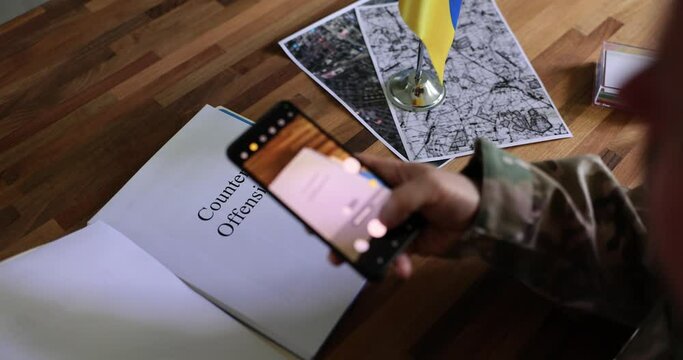 Military leader studies documents about the counteroffensive and takes pictures on smartphone. Theft of Ukrainian data on war between Ukraine and Russia