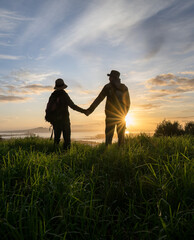 Couple standing on Mt Eden summit and looking at Rangitoto Island at sunrise. Auckland. Vertical format.