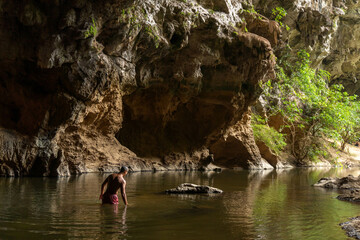 Sportive shirtless guy with a pink short swimming in xien lap cave, Thakhek loop, Laos